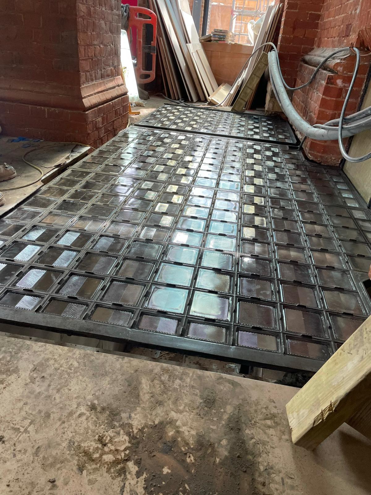 Restored cast iron pavement light showing heritage finish and renewed glazing